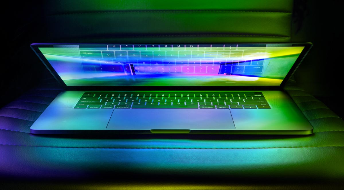 Open laptop on chair with neon coloured glare from screen